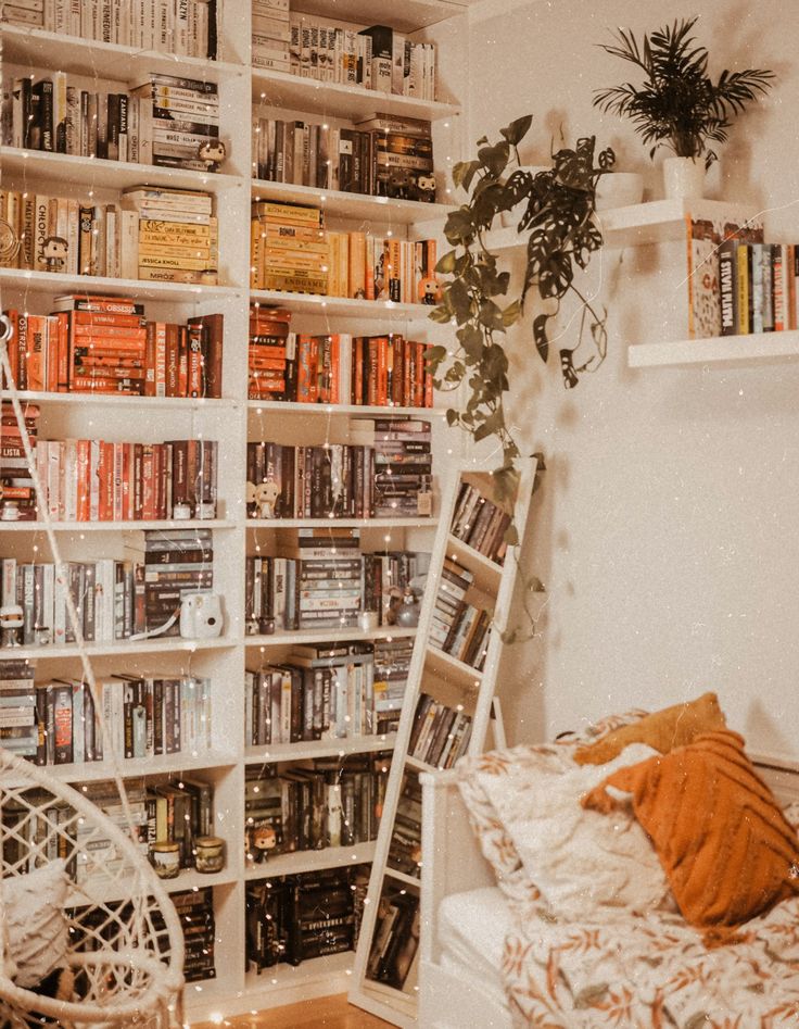 a living room filled with lots of books next to a white chair and book shelf