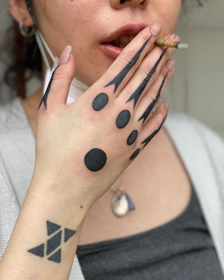 a woman holding her hands to her face with black ink on her fingers and hand