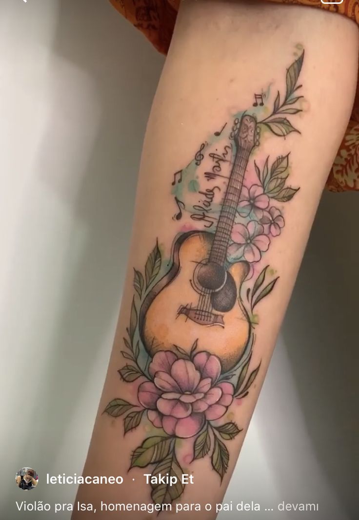 a woman's leg with a guitar tattoo and flowers on the bottom of it