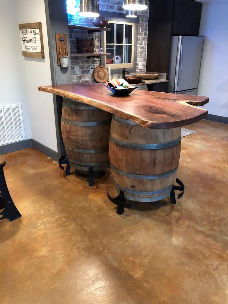 two wine barrels sitting on top of a wooden table in a kitchen next to a refrigerator