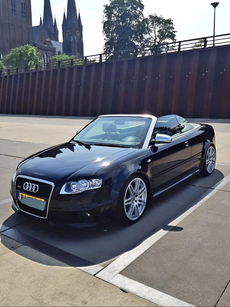 a black convertible car parked in a parking lot