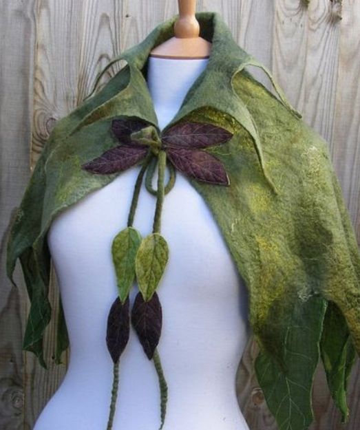 a white mannequin wearing a green and purple scarf with leaves attached to it