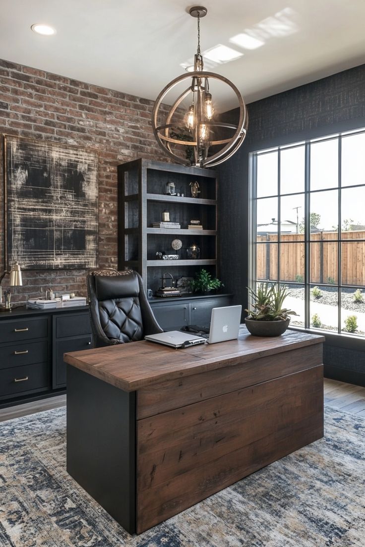 a desk with a laptop on it in front of a brick wall and large windows