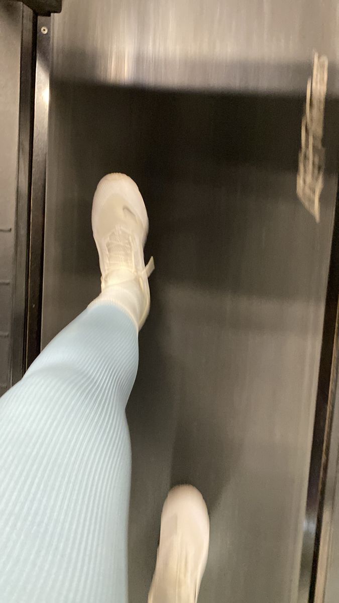 a person standing in front of a stainless steel wall with their foot on the glass door