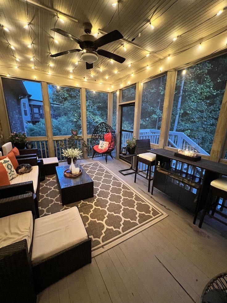 a living room filled with lots of furniture and lights hanging from the ceiling above it