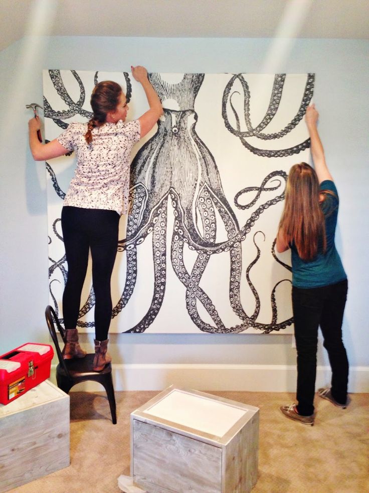 two women are painting an octopus on the wall