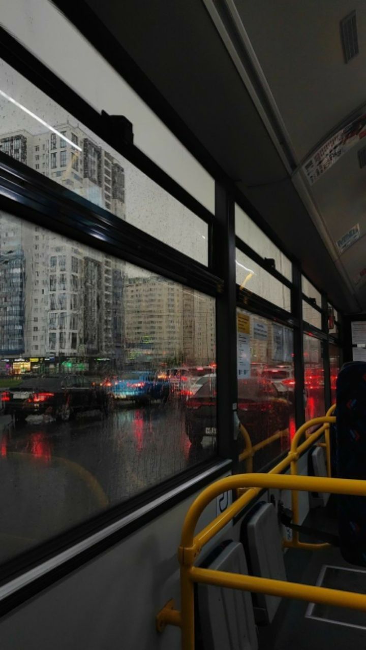 the city bus is traveling down the street in heavy rain and smoggy traffic