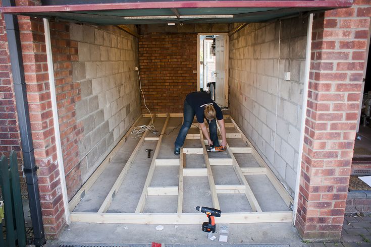 two men working on the inside of a house under construction with brick walls and floor joists