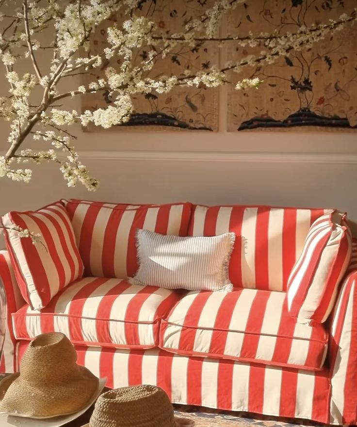 a red and white striped couch with two hats on the floor in front of it