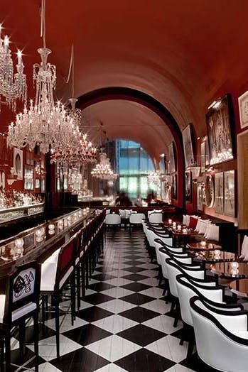 a restaurant with black and white checkered flooring, chandeliers hanging from the ceiling