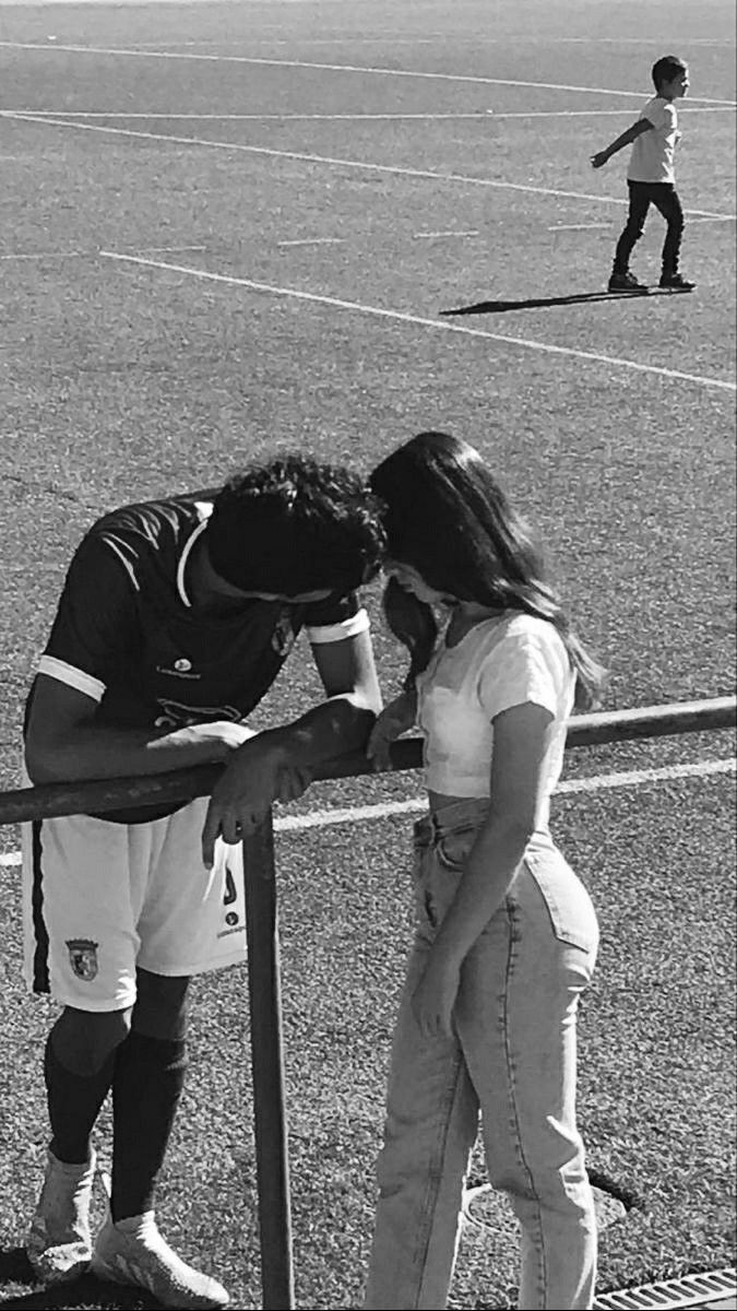 two people standing next to each other near a fence