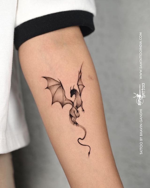 a small black and white dragon tattoo on the arm