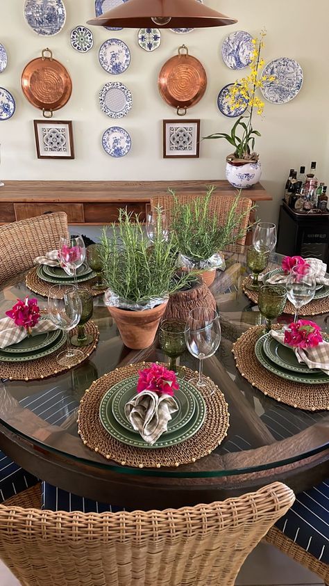 a dining room table set with place settings and plates on the wall above it, along with wicker chairs