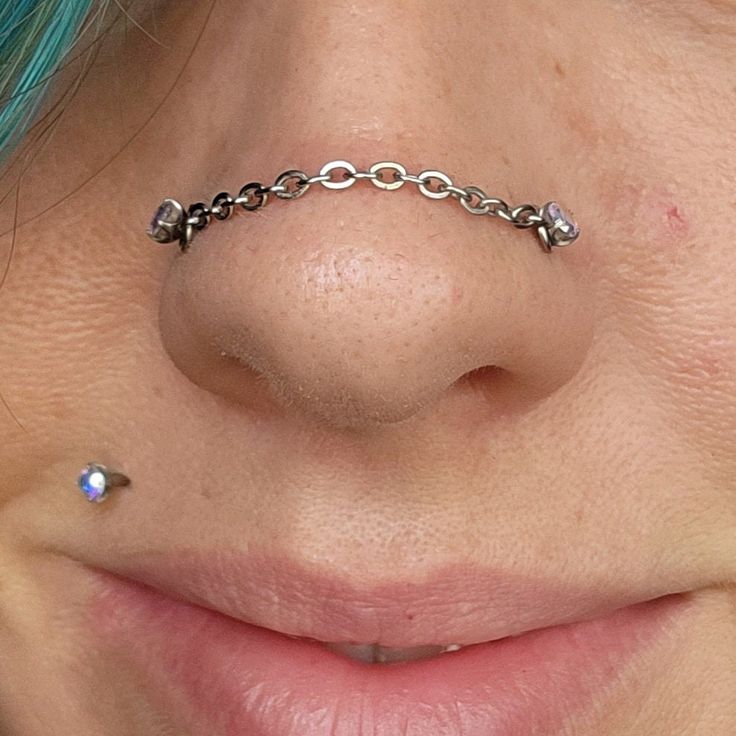 a woman's nose has a chain on it and is wearing a ring around her nose