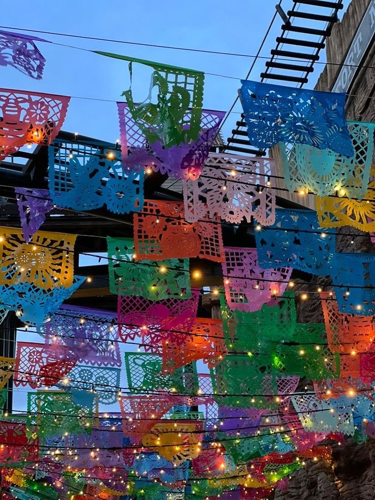 many colorful lights hanging from the ceiling in front of a building