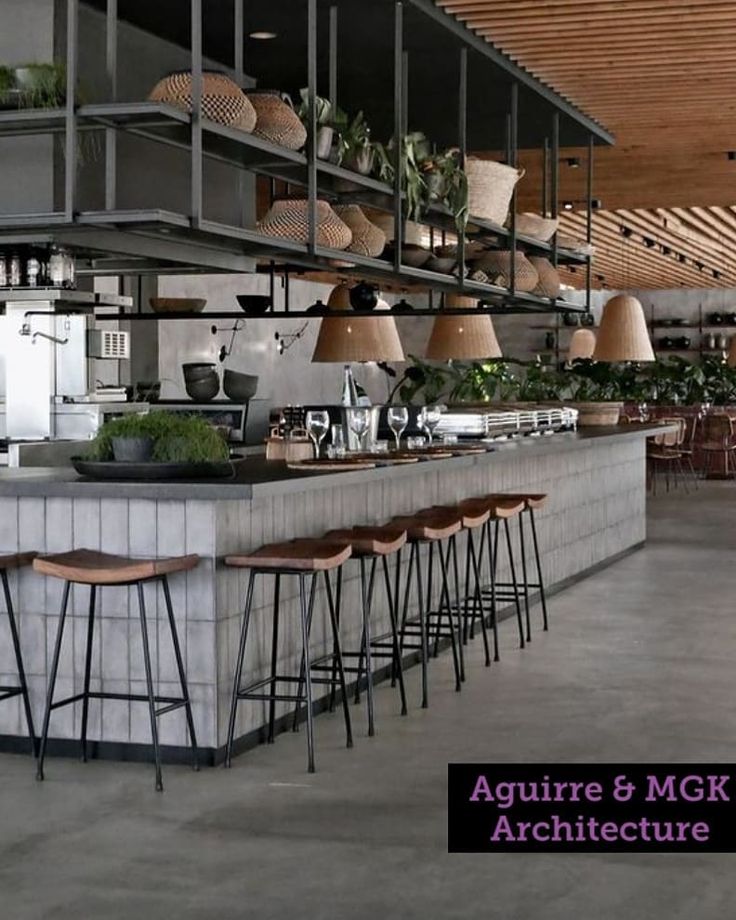 an industrial style bar with stools and plants on the shelves above it in a restaurant