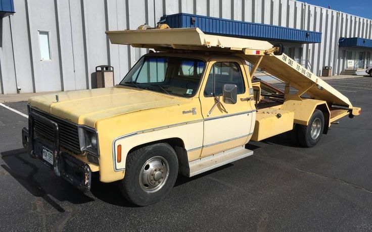 an old yellow truck parked in front of a building