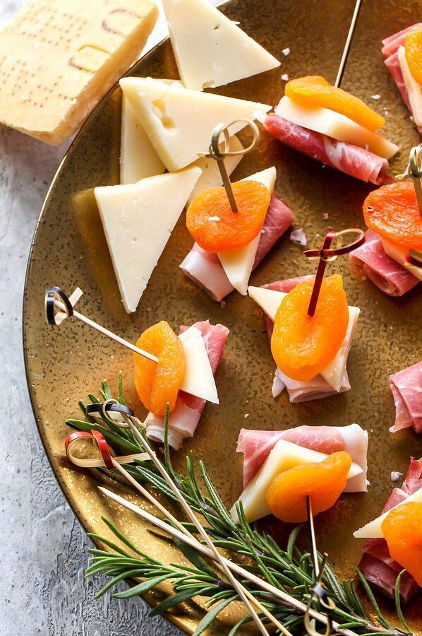 small appetizers are arranged on a plate with cheese, meats and herbs