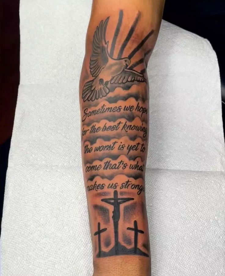 a person with a tattoo on their arm that has a cross and dove in it