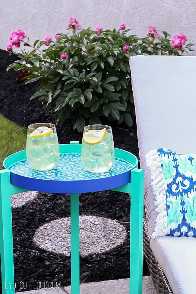 two glasses sitting on top of a blue table next to a white couch and pink flowers