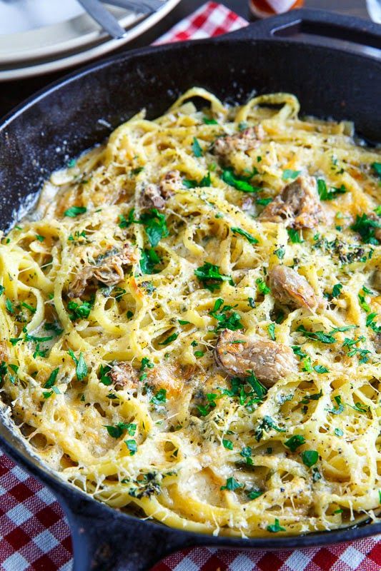 a skillet filled with pasta and meat covered in parmesan cheese, herbs