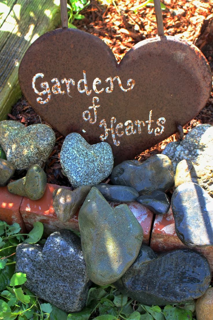 a heart shaped rock with the words garden of hearts written on it surrounded by rocks