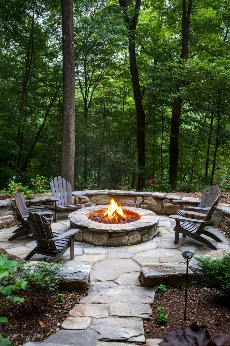 Backyard fire pit surrounded by Adirondack chairs in a forest setting. Fire Pit Ideas In The Woods, Landscape Ideas Fire Pit, Decomposed Granite Fire Pit, Fire Pit Yard Ideas, Fire Pit Ideas Sloped Backyard, Firepits Backyard Ideas Pavers, Fire Pit Brick Pavers, Fire Pit Ideas Backyard Retaining Wall, Large Outdoor Firepits