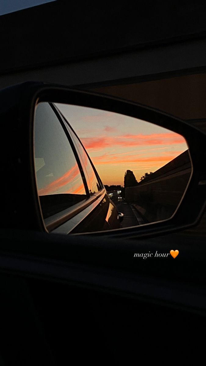 the rear view mirror of a car reflecting a sunset