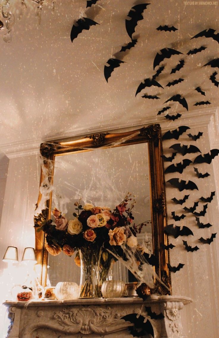 a mirror with bats on the wall above it and flowers in vase next to it