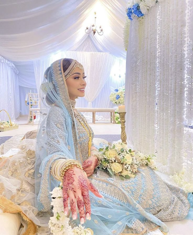 a bride sitting on the floor with flowers in her hand and wearing a bridal outfit