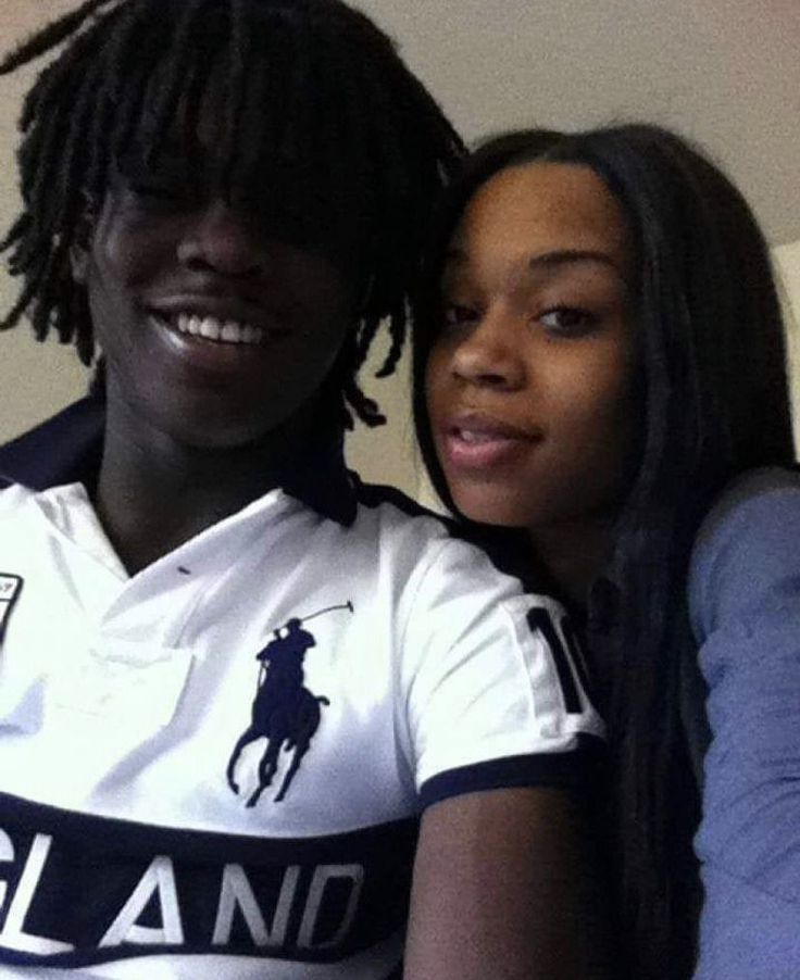 two young women sitting next to each other in front of a white wall and one is wearing a polo shirt