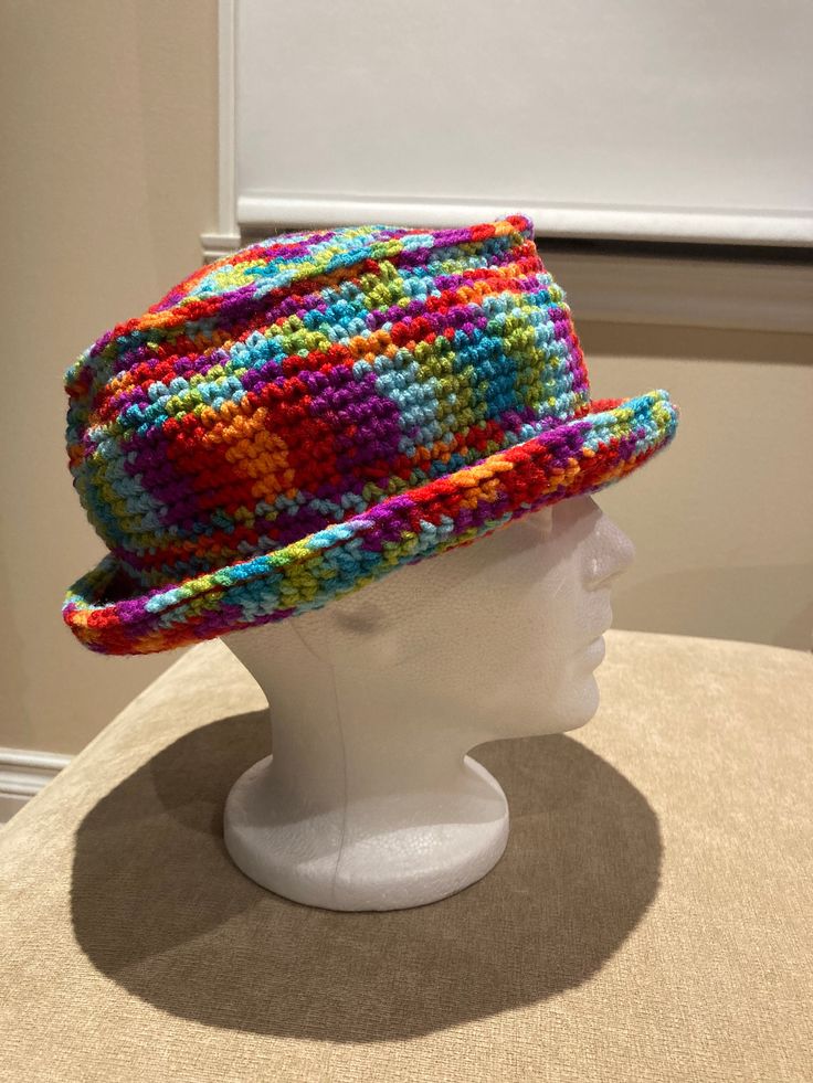 a white mannequin head wearing a multicolored knitted hat on display