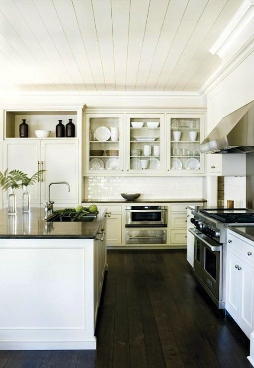 a kitchen with white cabinets and black counter tops is pictured in this image, there are dishes on the shelves above the stove