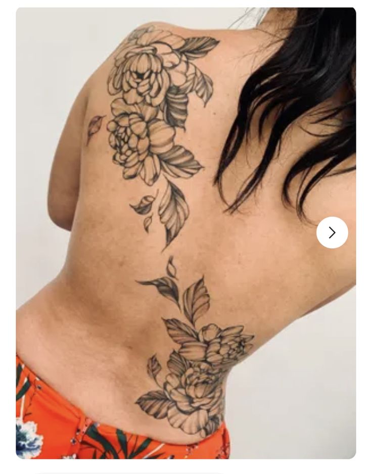 the back of a woman's body with flowers tattooed on her upper and lower back