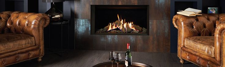 a living room with two leather chairs and a fire place in the center, next to a coffee table