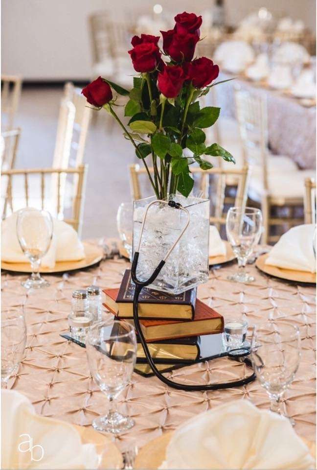 a vase filled with red roses sitting on top of a table next to wine glasses