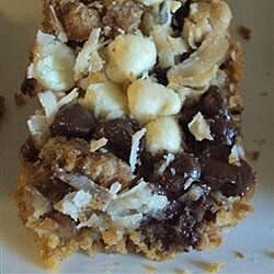 a close up of a piece of food on a white plate with nuts and chocolate