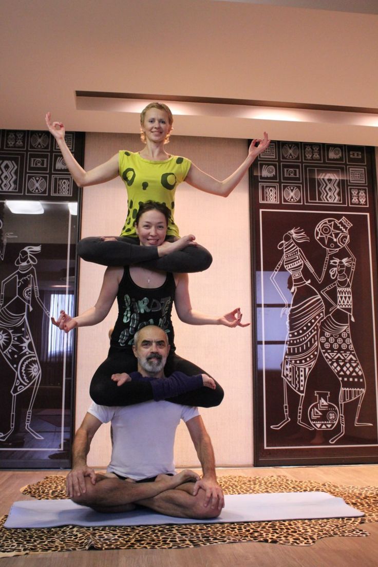 three people are doing yoga poses in front of an art work on the wall behind them