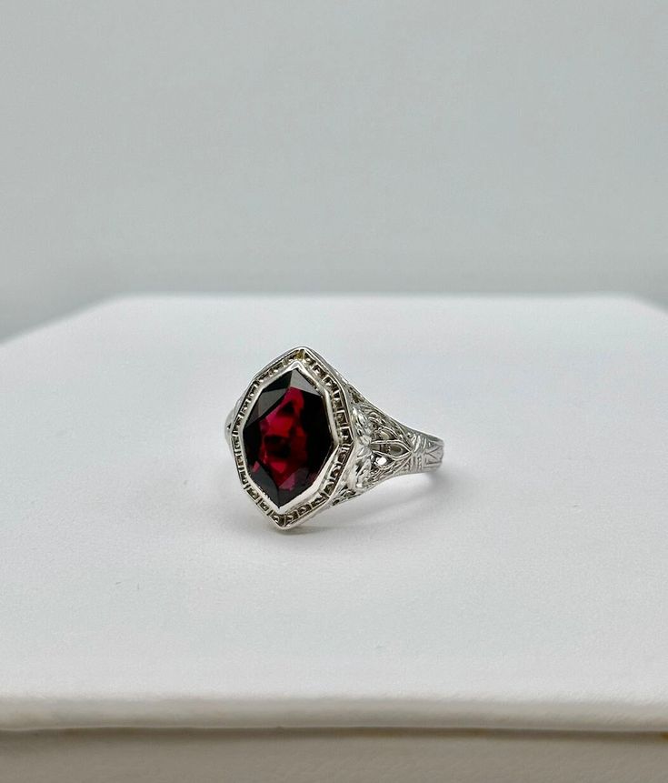 This stunning vintage ring features intricate filigree work and the most unique shaped stone. The stone's coloring resembles a garnet with its deep and rich red hue. This ring is a size 6.25. Classic Ruby Ring With Gemstone Accents For Formal Occasions, Formal Garnet Rings With Gemstone Accents, Formal Garnet Burgundy Ring, Oval Garnet Jewelry With Intricate Design, Formal Burgundy Garnet Ring, Red Victorian Filigree Ring For Anniversary, Victorian Red Oval Filigree Ring, Heirloom Ruby Ring With Gemstone Accents For Formal Occasions, Vintage Oval Garnet Birthstone Ring