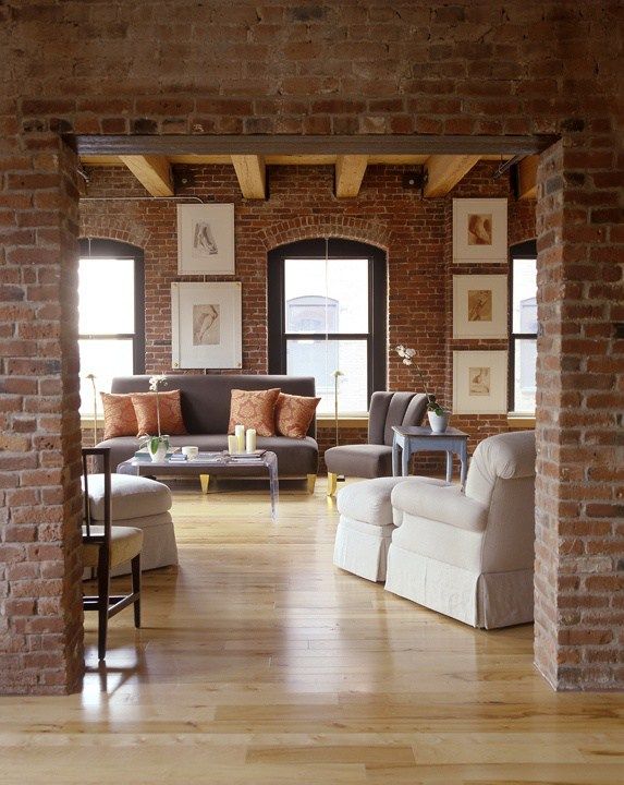 an open living room with brick walls and wooden floors is seen in this image from the doorway