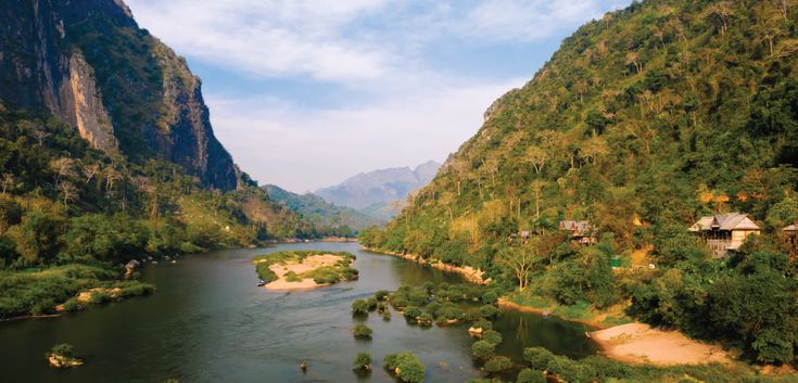 an aerial view of a river surrounded by mountains and greenery in the foreground