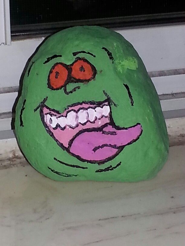 a rock with a face painted on it sitting in front of a window sill