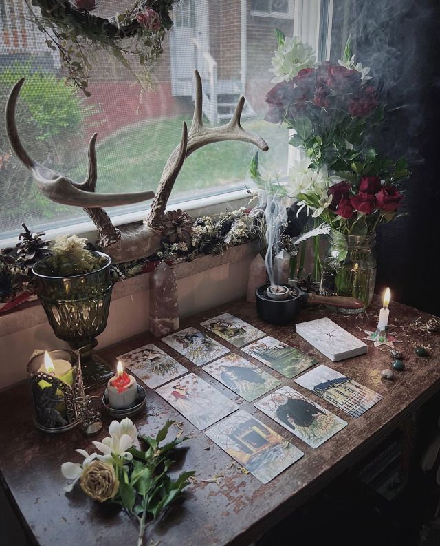 a table with cards, candles and flowers on it in front of a large window