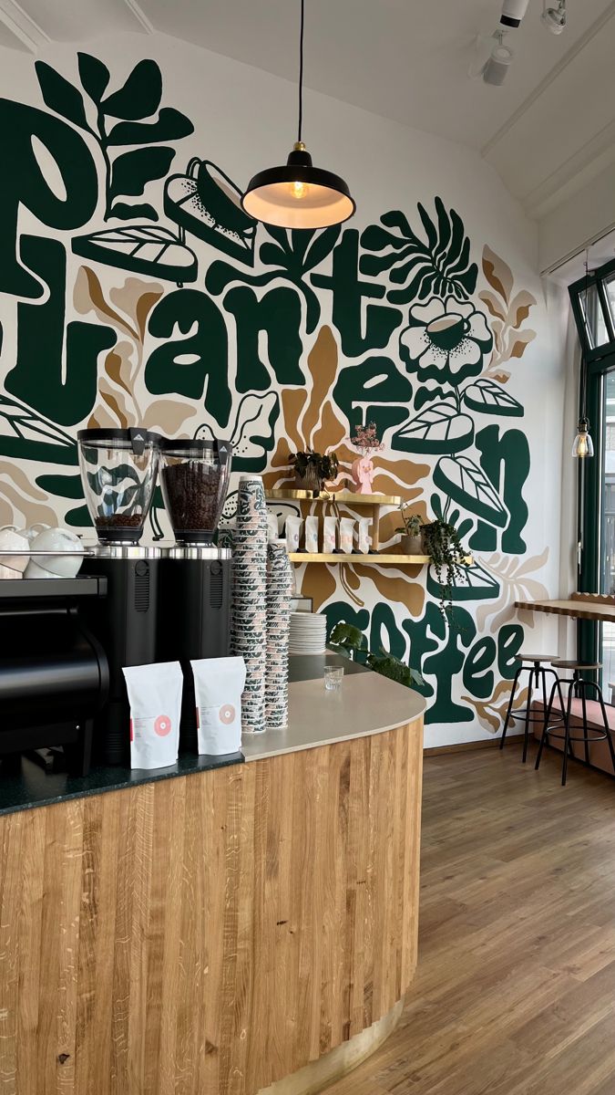 the interior of a coffee shop with green and brown designs on the wall behind the counter