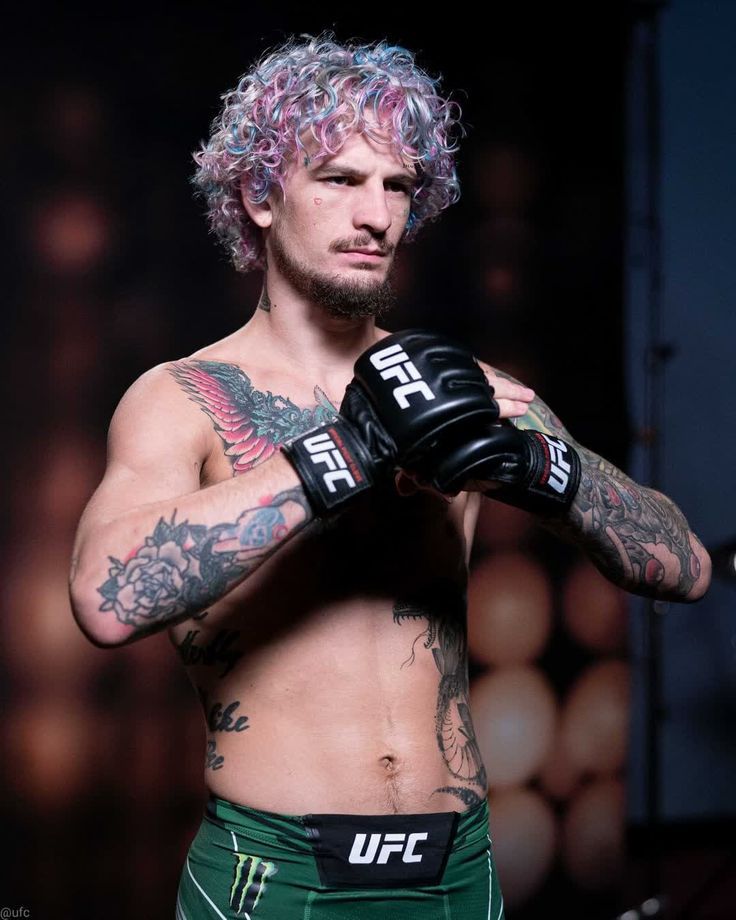 a man with pink hair and tattoos wearing boxing gloves