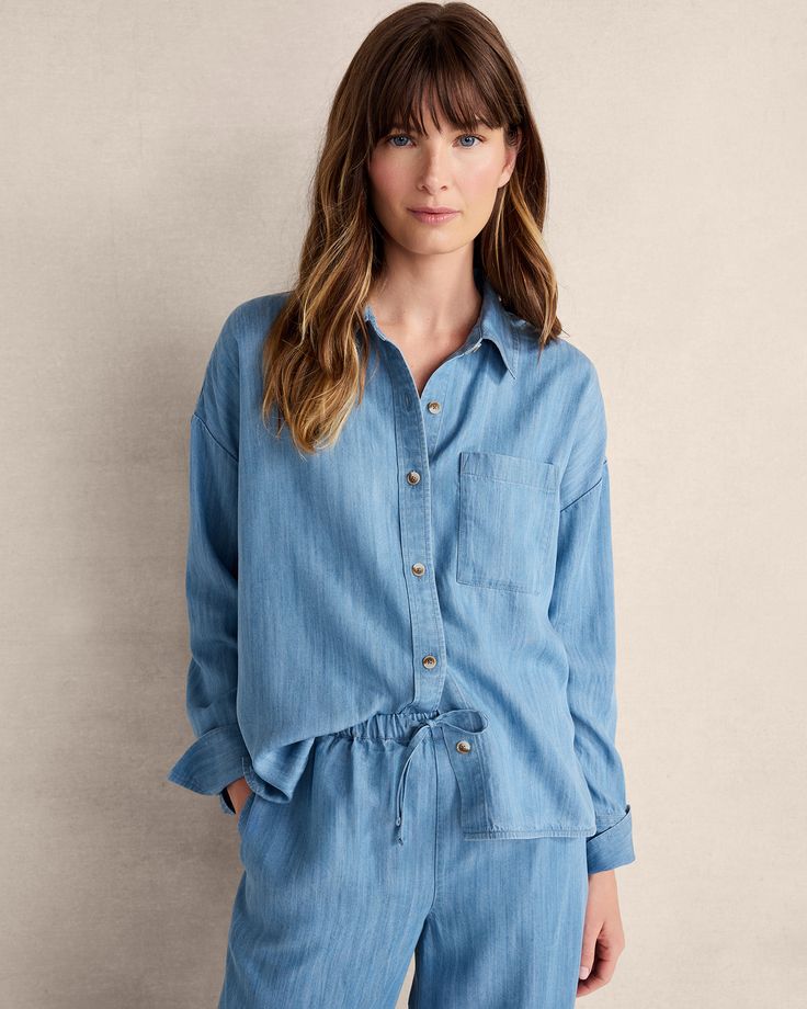 A timeless chambray button-up fashioned from sustainable TENCEL™ fabric. Dyed with natural indigo, slight variations in the color make each shirt unique. Pairs beautifully with our matching drawstring pants. | This product’s overall fiber content is made with at least 50% of an environmentally preferred fiber. Learn more about our efforts to design planet-friendly apparel here. Details + Design: Long sleeves. Button up. Hits at hip. 23 1/2” length. Material: 100% TENCEL™ LyocellCare: Machine Was Chambray Button-up Shirt, Light Wash Chambray Button-up Top, Blue Chambray Button-up Shirt, Long Quilted Coat, Washed Chambray Denim Button-up Top, Chambray Button-up Tops With Button Closure, Owl Sweater, Cocoon Sweater, Textured Knit Sweater