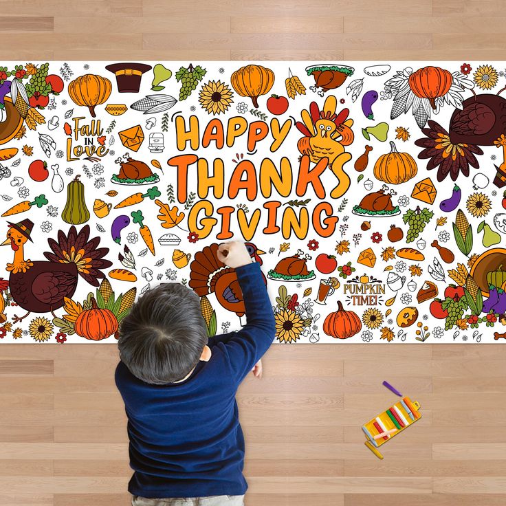 a young boy is drawing on a thanksgiving themed wallpaper that says happy thanks giving