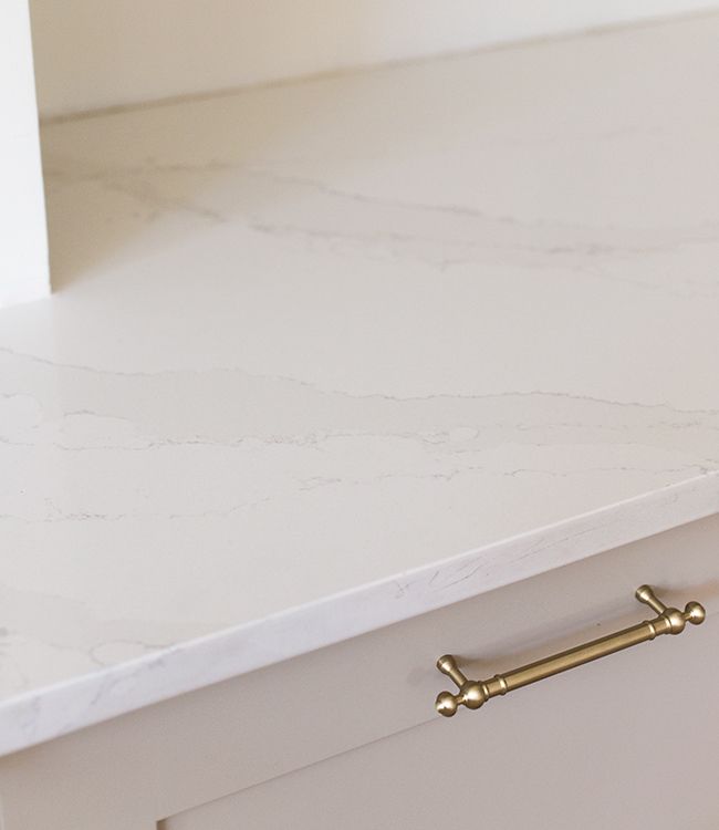 a white counter top with brass handles and a drawer on one side that is open