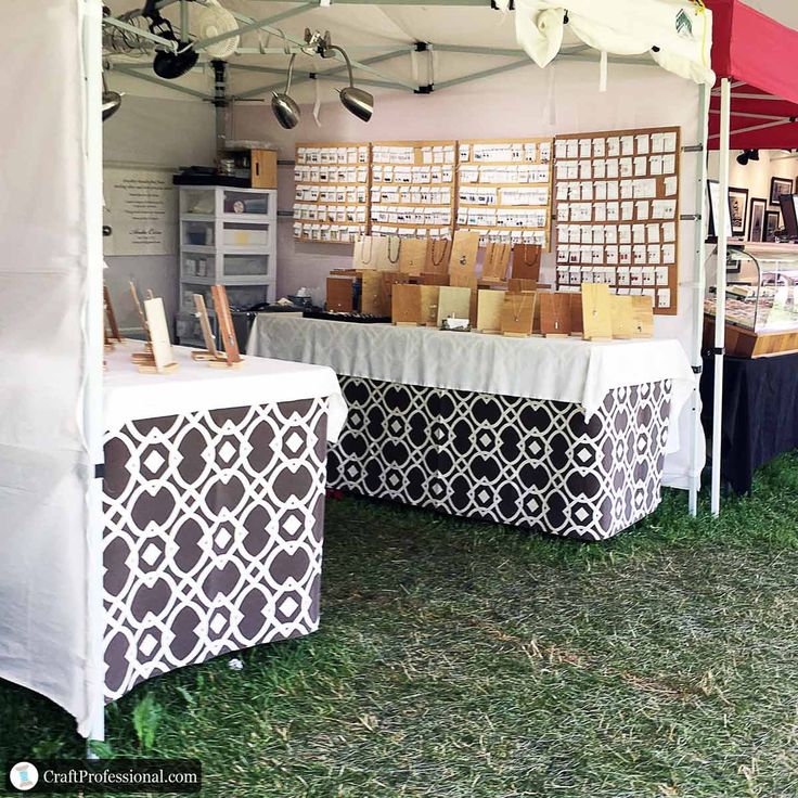 an outdoor market with several tables covered in black and white cloths, including boxes