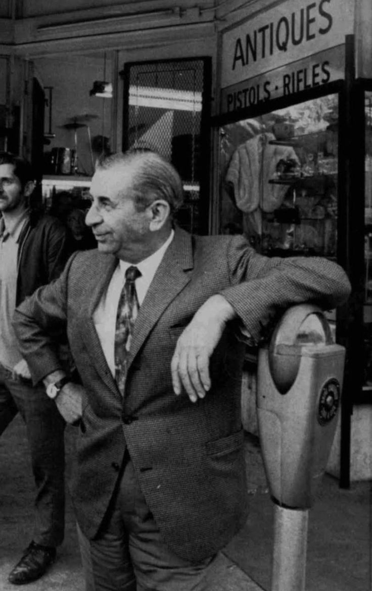 two men standing next to each other in front of a store with signs on it